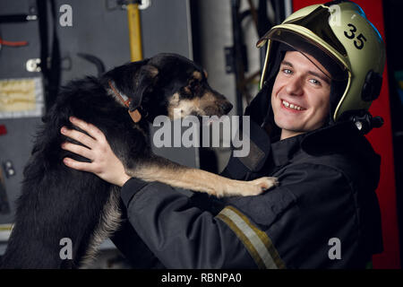 Ritratto di felice vigile del fuoco nel casco con il cane Foto Stock