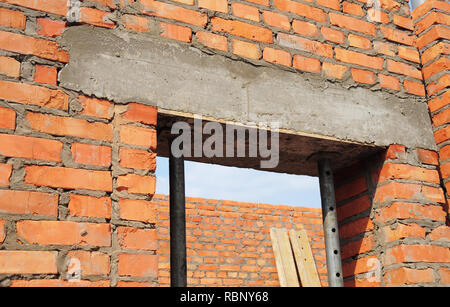 Edificio di costruzione della casa. Finestra, porta architrave in calcestruzzo con barra di ferro sul mattone casa non finita la costruzione. Foto Stock