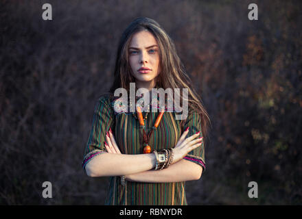 Ritratto di giovane bella ragazza hippie sul tramonto all'esterno. Bracci incrociati Foto Stock