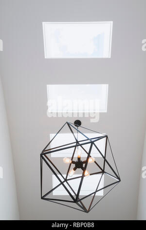 Finestre lucernario e acciaio nero esagonale di apparecchio di illuminazione con cinque in vetro trasparente lampadine appese sopra la scala all'interno di un cubo moderno stile home Foto Stock