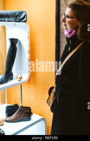 Donna ammirando le scarpe di cuoio in negozio windows di una calzatura store a Parigi Foto Stock