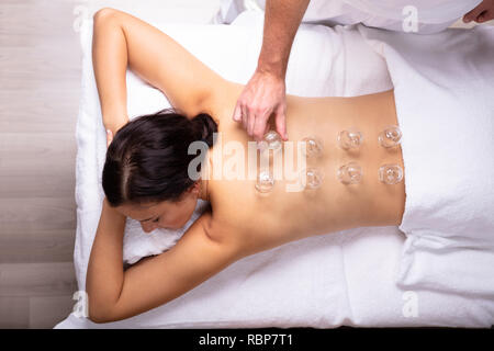 Rilassata giovane donna ricevere trattamento Cupping sulla sua schiena In Spa Foto Stock