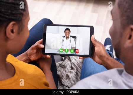 Close-up di un Africano giovane Videoconferenze con felice medico donna sulla tavoletta digitale Foto Stock