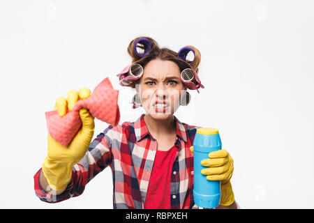 Arrabbiato casalinga con bigodini nei capelli in piedi isolato su sfondo bianco, azienda di detergenti Foto Stock