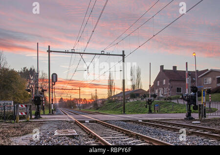 Klimmen-Ransdaal, Paesi Bassi, 18 Novembre 2018: passaggio a livello della ferrovia nei pressi della stazione ferroviaria in un colorato Cielo di tramonto Foto Stock