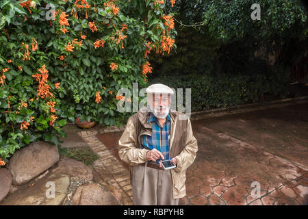Felice l'uomo senior per la messaggistica di testo su un mobile smart phone in un giardino Foto Stock