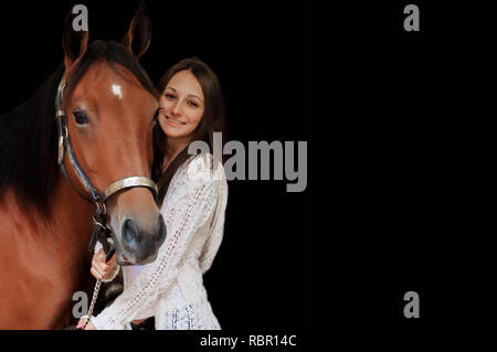 Copyspace disponibile in questo soft focus ritratto della ragazza in piedi accanto a cavallo tenendolo redini del. Foto Stock