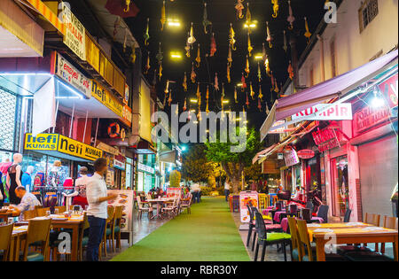 ANTALYA, Turchia - 9 Maggio 2017: la stretta Inonu Street è rivestito con tourist cafes e ristoranti e decorate con ombrelloni colorati nel cielo, o Foto Stock