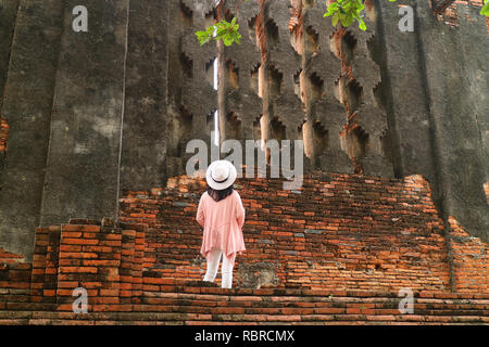 Turista femminile guardando false finestre del Royal Vihara al Wat Mahathat tempio in seno al parco storico di Ayutthaya, sito archeologico in Thailandia Foto Stock