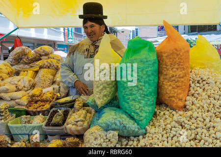 Indossando un tradizionale Bowler cappello, una vecchia signora indigena di sacchetti e vende i suoi grani, una scena duplicato in ogni mercato in Bolivia. Foto Stock
