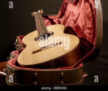 Acoutic guitar si siede in un rosso foderata di velluto caso Foto Stock