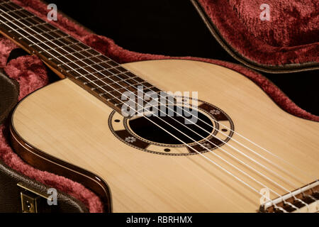 Acoutic guitar si siede in un rosso foderata di velluto caso Foto Stock