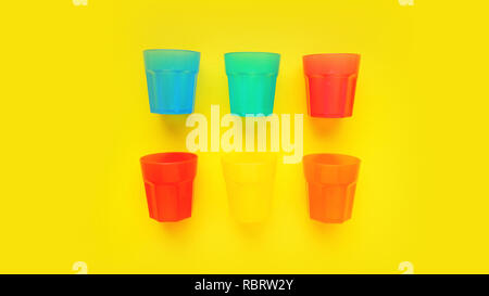 Bicchiere di plastica di vario colore isolato su sfondo giallo - estate brillante concetto di design e banner Foto Stock