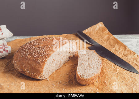 Pane appena sfornato pagnotta di pane integrale con crusca sulla carta da forno. Tagliato a coltello Foto Stock