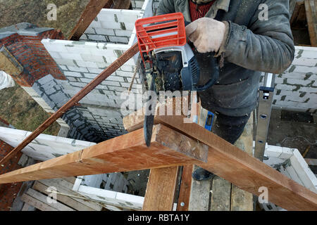 Lavoratori tagliare le travi a vista sul tetto della casa di sega a nastro Foto Stock