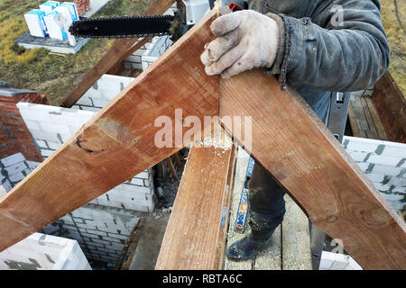 Lavoratori tagliare le travi a vista sul tetto della casa di sega a nastro Foto Stock