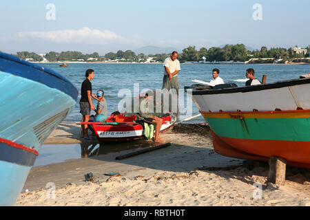 I pescatori locali cancellano le reti tra le barche sulla spiaggia di sabbia di Hammamet Foto Stock