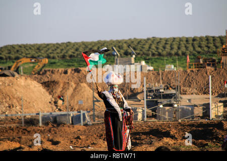 Una donna battenti bandiera della Palestina durante le dimostrazioni tra i cittadini palestinesi e forze di occupazione israeliane in segno di protesta contro il riconoscimento del Presidente americano Trump Gerusalemme come capitale di Israele ad est della città di Gaza. Foto Stock