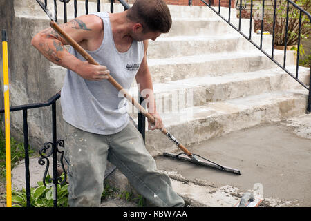 Workman smussa un rivestimento skim di cemento su una vecchia scalinata. Foto Stock