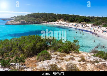 Bella spiaggia affollata con acqua turchese nella stagione estiva, Cala Modrago, Mallorca Foto Stock