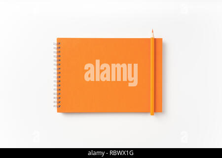 Concetto di Design - vista superiore della spirale arancione notebook, pagina bianca e matita isolato su sfondo per mockup Foto Stock