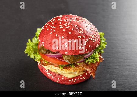 Colorate di rosso gli hamburger. In casa americana hamburger di pollo hamburger withbeetroot panini e verdure. Cibo alla moda. sfondo di ardesia. Foto Stock