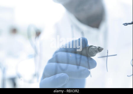 Scienziato scrive la formula su un bordo di vetro Foto Stock