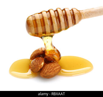 Il miele che gocciola dalla cucchiaia di mandorle isolati su sfondo bianco Foto Stock