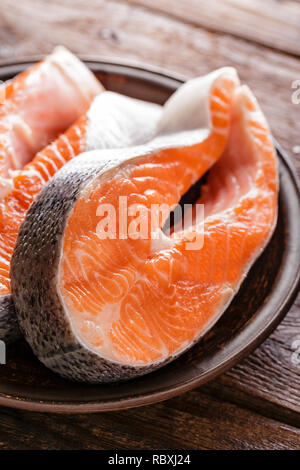 La cottura di due crudo fresco salmone tranci di pesce su legno tavolo rustico closeup Foto Stock
