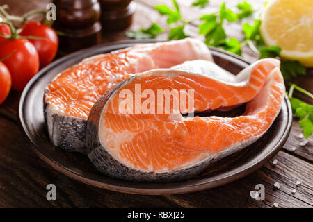 La cottura di due crudo fresco salmone tranci di pesce su legno tavolo rustico closeup Foto Stock