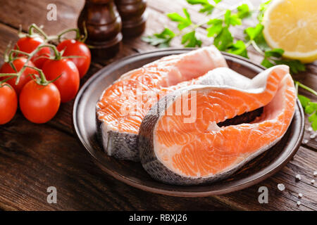 La cottura di due crudo fresco salmone tranci di pesce su legno tavolo rustico closeup Foto Stock