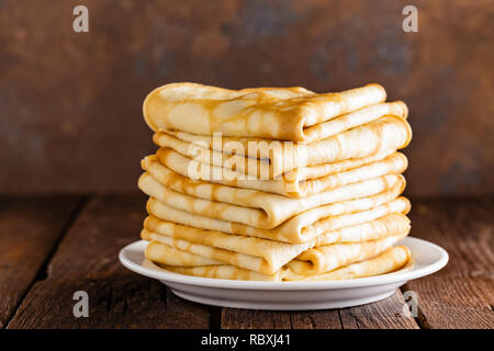 In casa crespelle sottili stack, frittelle avvolto su legno tavolo rustico Foto Stock