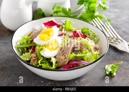 Insalata di tonno in un recipiente. Cucina mediterranea. Insalata fresca con tonno in scatola. Una sana cucina dietetica Foto Stock