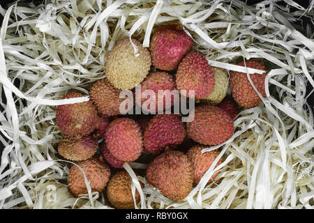 Pila di litchi Esotici frutti sul beige segatura di legno Foto Stock