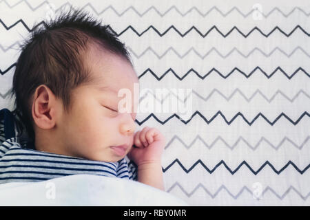 Chiusura del piccolo grazioso asiatiche neonato bimbo che dorme sul letto matrimoniale in camera da letto per bambini con copia spazio. famiglia, sano, vita e concetto di relazione. Foto Stock