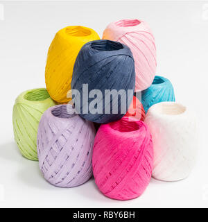 Alcune palline di rafia colorata su una superficie bianca Foto stock