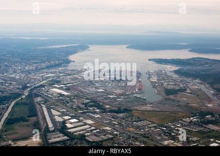 Porto di Tacoma, dove il fiume Puyallup (sinistra) alimenta nella baia di inizio. Le gru del porto artificiale di linea le vie navigabili. Interstate Highway I-5 attraversa in primo piano, passando sopra il fiume Puyallup sul Puyallup River Bridge. Dietro di esso tre ponti più cross, Route 509, Lincoln Ave, e E Xi San Centro di Tacoma è in alto a sinistra. Attraverso la baia è Vashon isola sulla destra e la Olympic Penninsula sulla sinistra in distanza. Foto aerea del porto di Tacoma. Foto Stock