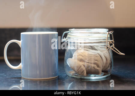 Un boccale di blu e un vasetto di bustine di tè su un piano di lavoro di una cucina. Foto Stock