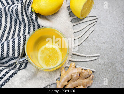 Il tè allo zenzero con fettina di limone e una coppa di vetro. Un sano tea time con zenzero fresco. Scena invernale, vista dall'alto. Foto Stock