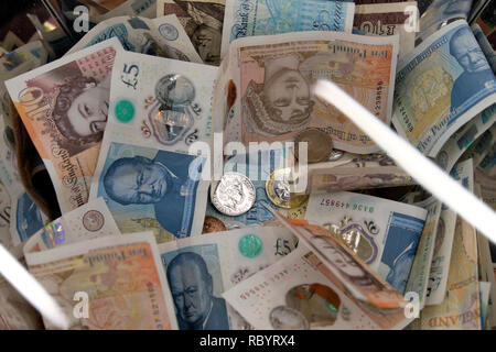 Un mucchio di carta inglese sterling polimero denaro Winston Churchill £5 nota Jane Austen £10 Queen e raccolta di banconote Box a Londra UK KATHY DEWITT Foto Stock