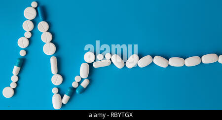 Medicinali bianca, rotonda a forma di cuore ad pillole isolato su sfondo blu. Compresse a forma di una linea di un ritmo cardiaco su un pastello blu sullo sfondo. Ca Foto Stock