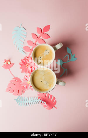Vista da sopra con due tazze di caffè e moderno artigianato origami fiori di carta copia spazio. La donna il giorno 8 marzo. sfondo rosa. Donna ed elegante Foto Stock