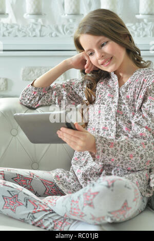 Ritratto di bambina in pigiama con tavoletta digitale in casa Foto Stock