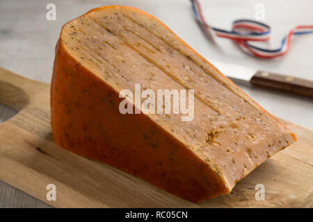 Pezzo di tre anni di cumino olandese formaggio su di un tagliere di legno Foto Stock