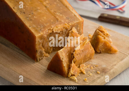 Pezzo di tre anni di cumino olandese formaggio con pasticcini su un tagliere di legno Foto Stock