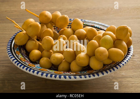 Fresh immaturo date giallo su un piatto di portata Foto Stock