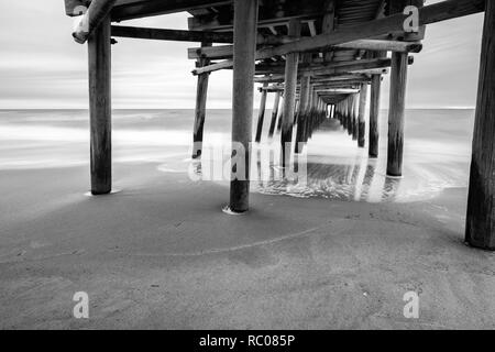 Come il sole sorge dietro la pesca Sandbridge Pier, onde crash - sotto-temi: prospettica, pace lunga esposizione, Otturatore lento, misty Foto Stock