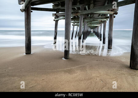 Come il sole sorge dietro la pesca Sandbridge Pier, onde crash - sotto-temi: prospettica, pace lunga esposizione, Otturatore lento, misty Foto Stock