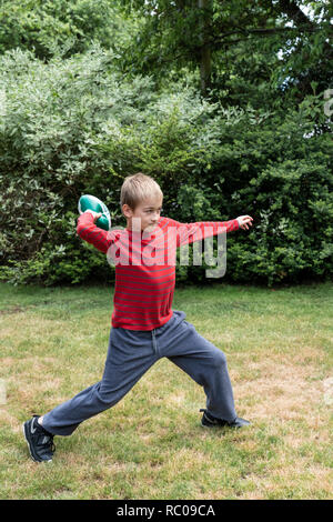 Dieci anni di vecchio ragazzo gettare un calcio nel suo cortile. (MR) Foto Stock