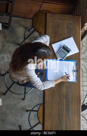 Donna tenendo la penna e la ricerca di informazioni nei documenti Foto Stock